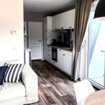 Wohnbereich mit Sofa, Küche und Balkontür.