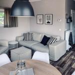 Wohnbereich mit Sofa, Sessel und Esstisch. Fenster mit Blick nach draußen.