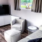 Wohnzimmer mit Sofa, Sessel und Fernseher. Fenster mit Blick auf Garten.