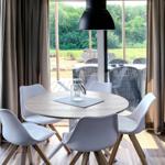 Runder Tisch mit vier Stühlen vor großem Fenster mit Blick auf Terrasse.