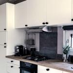 Küche mit weißen Schränken, Holz Arbeitsplatte und Gasherd.