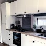 Küche mit weißen Schränken, Holzplatte, Spüle und Fenster.