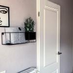 Wandregal mit Pflanze und Kissen neben Tür mit Haken.