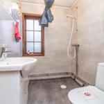 Badezimmer mit Waschbecken, Dusche und Toilette. Fenster mit Holzrahmen.