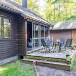 Holzhaus mit Terrasse und Garten. Sicht auf Schlauch und Tisch.