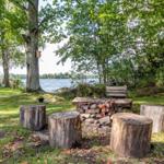 Feuerstelle mit Holzstümpfen und Blick auf den See.
