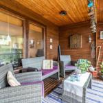 Terrasse mit Sitzgruppe, Pflanzen und Holzwand. Durchgehende Glasfront.