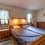 Schlafzimmer mit Holzbett, zwei Fenstern und Nachttischen.