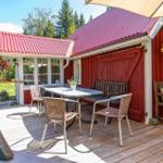 Terrasse mit Tisch, Stühlen und Sitzbank vor rotem Haus mit rotem Dach.
