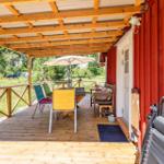 Terrasse mit Tisch, Stühlen und Sonnenschirm neben rotem Container.