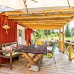 Terrasse mit Tisch, Bänken und Sitzgelegenheiten unter einem Dach.