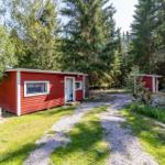Rotes Holzhaus mit weißem Rahmen im Wald. Kiesweg führt zur Tür.