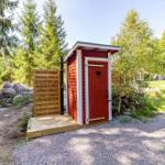 Rotes Holzbadhaus mit Herzförmigem Fenster und Dusche im Freien.