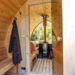 Holzsauna mit Sitzbänken, Ofen und Blick in den Wald.