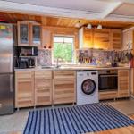 Küche mit Holzmöbeln, Spüle, Waschmaschine und Kühlschrank.