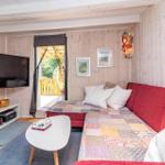 Ein Wohnzimmer mit rotem Sofa, Fernseher und Blick auf die Terrasse.