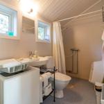 Badezimmer mit Waschmaschine, Toilette und Dusche.