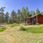 Rotes Holzhaus mit Veranda, umgeben von Wald und See.