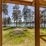 Von der Terrasse aus Blick auf See und Wald mit Picknicktisch und Stein.