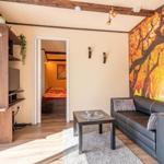 Wohnbereich mit Sofa, Couchtisch und Wandbild. Im Hintergrund ist ein Schlafzimmer sichtbar.