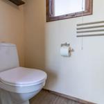 Toilette mit Toilettenpapierhalter, Heizkörper und Fenster