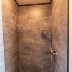 Duschkabine mit floral gemusterter Wand und Duschbrause
