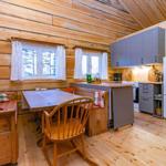 Kitchen with dining area, wooden walls, windows, and cabinets.