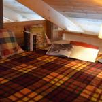A loft bed with a blanket, pillows, and a lamp.