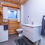 Bathroom with sink, toilet, and window with wooden wall.