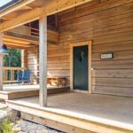 Wooden porch with blue seating and green door.