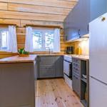 Kitchen with wooden walls, windows, worktop, and refrigerator.
