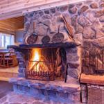 Stone fireplace with burning fire, above hanging pans and tools.