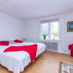 Schlafzimmer mit Bett, rotem Sofa und Fenster mit Blick.