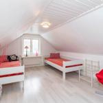 Zimmer mit zwei Betten, rotem Sessel und Fenster