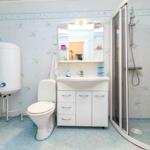 Badezimmer mit Dusche, Waschbecken und Toilette. Wandverkleidung mit Muster.