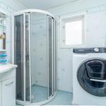 Badezimmer mit Dusche, Waschbecken und Waschmaschine.