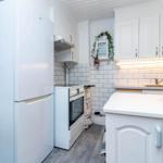 Küche mit weißen Schränken, Kühlschrank und Herd. Fliesenwand und Arbeitsplatte.