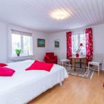Ein Schlafzimmer mit Doppelbett, kleinem Bett, roten Vorhängen und Holzboden.