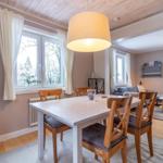 Essbereich mit Tisch und Stühlen, Wohnbereich mit Sofa und Fenstern.
