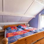 Bedroom with wooden bed, blue walls, and sloped ceiling.