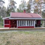 Red wooden house with terrace and garden surrounded by trees