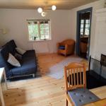 Living room with sofa, armchair, and fireplace. Wooden floor and window with view outside.