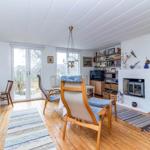 Wohnraum mit Bett, Sitzgelegenheiten und Kamin. Holzboden und große Fenster.