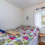 Schlafzimmer mit Bett, Fenster und Holzstuhl.
