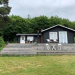 Schwarze Hütte mit Terrasse, Garten und Bäumen im Hintergrund.