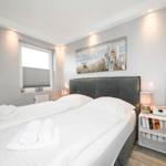 Schlafzimmer mit Bett, Nachttisch und Wandbild. Fenster mit Jalousie.