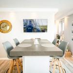 Essbereich mit Tisch und Stühlen, Wanduhr und Bild an der Wand.