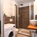 Bad mit Dusche, Waschmaschine und Waschtisch mit Keramikschale.