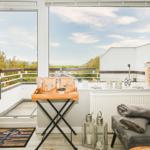 Balkon mit Sicht auf Grünflächen und Himmel. Möbel und Dekoration sind sichtbar.