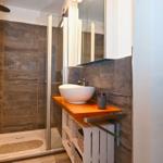 Dusche mit Glaswand, Waschbecken auf Holzplatte und Spiegelschrank